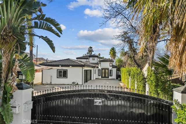 exterior space featuring a fenced front yard, a tiled roof, a gate, and stucco siding