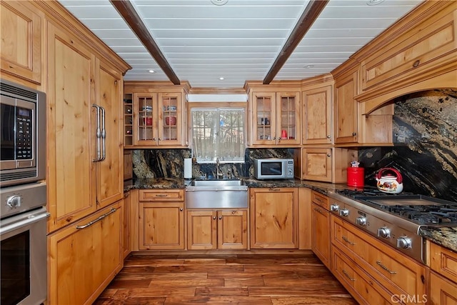 kitchen with stainless steel appliances, dark stone counters, dark hardwood / wood-style flooring, decorative backsplash, and sink