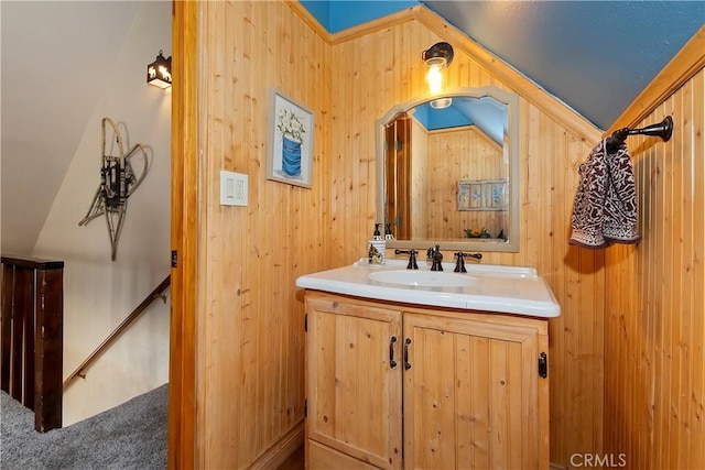 bathroom featuring vanity, wooden walls, and lofted ceiling