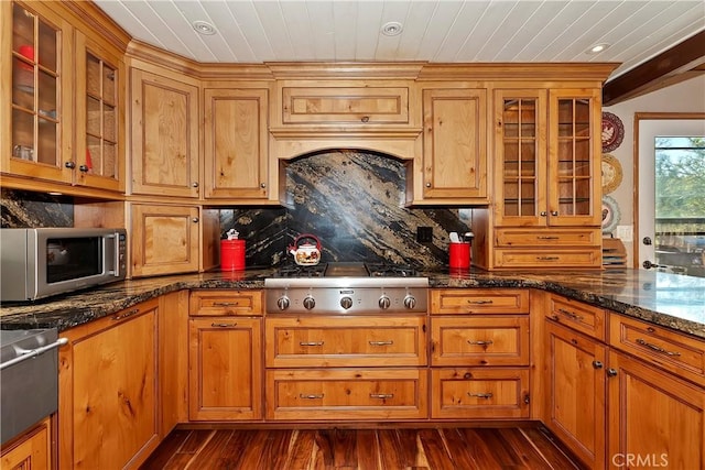 kitchen with dark stone counters, stainless steel appliances, dark hardwood / wood-style floors, and tasteful backsplash