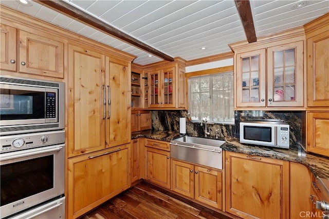 kitchen featuring sink, appliances with stainless steel finishes, tasteful backsplash, dark stone counters, and dark wood-type flooring