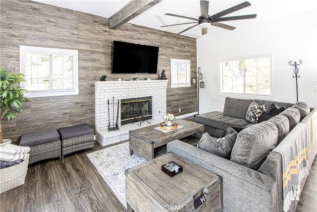 living room with wood walls, ceiling fan, a fireplace, beam ceiling, and dark hardwood / wood-style flooring