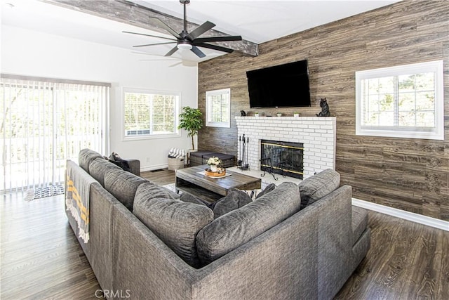 living room with a fireplace, beam ceiling, dark hardwood / wood-style flooring, and wooden walls