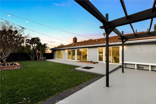 back house at dusk featuring a pergola, a yard, and a patio