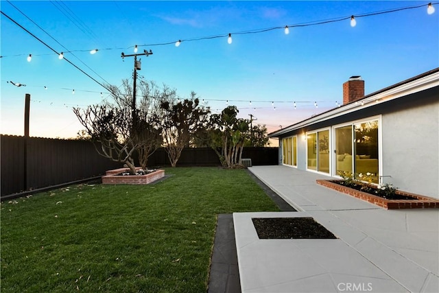 yard at dusk featuring a patio