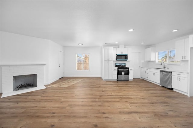 kitchen featuring white cabinets, appliances with stainless steel finishes, a fireplace, and sink