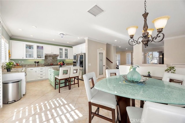 tiled dining space featuring ornamental molding and an inviting chandelier