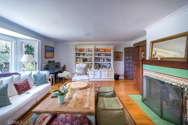 living room with ornamental molding, light hardwood / wood-style floors, and a tiled fireplace