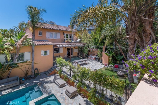 back of property with a fenced in pool, a balcony, outdoor lounge area, and a patio