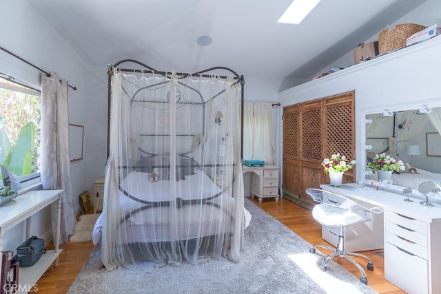 bedroom with light hardwood / wood-style floors and vaulted ceiling with skylight