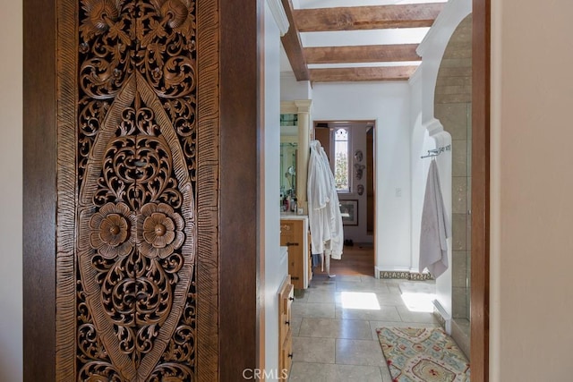 corridor featuring light tile patterned floors and beamed ceiling