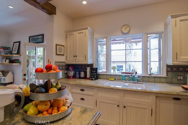 kitchen with sink, a healthy amount of sunlight, white cabinets, and tasteful backsplash