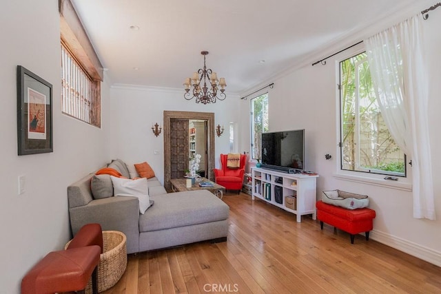 living room with ornamental molding, a notable chandelier, and light hardwood / wood-style floors