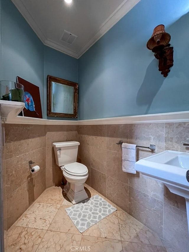 bathroom featuring toilet, tile walls, and ornamental molding