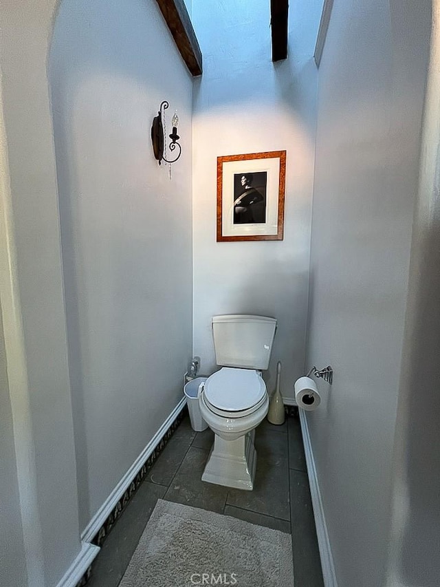 bathroom featuring toilet, tile patterned floors, and beamed ceiling