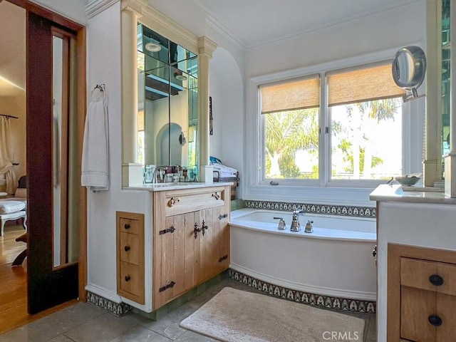 bathroom with ornamental molding, a tub to relax in, tile patterned flooring, and vanity