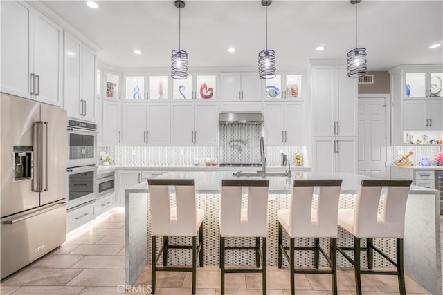 kitchen featuring a kitchen island with sink, white cabinets, a kitchen breakfast bar, hanging light fixtures, and stainless steel appliances