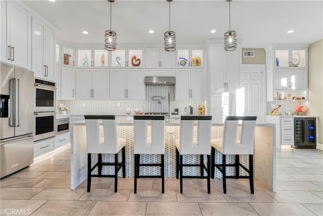 kitchen with white cabinetry, a breakfast bar, hanging light fixtures, and appliances with stainless steel finishes