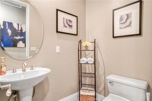 bathroom with toilet, a sink, visible vents, and baseboards