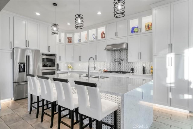 kitchen with white cabinetry, extractor fan, an island with sink, and appliances with stainless steel finishes