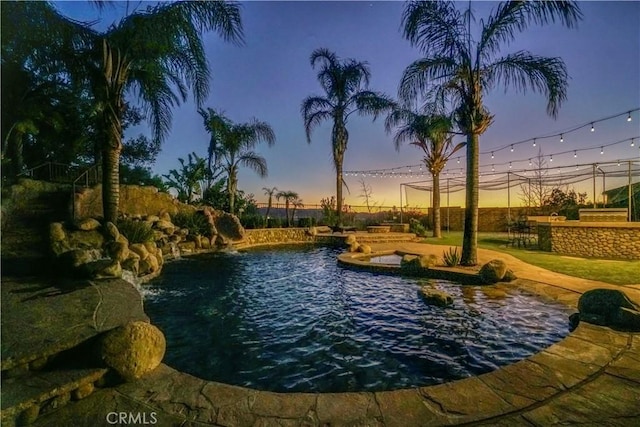 pool at dusk featuring pool water feature