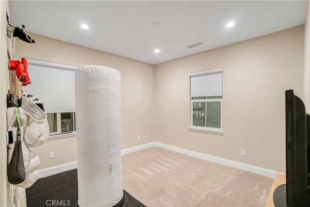 carpeted spare room featuring baseboards, visible vents, and recessed lighting