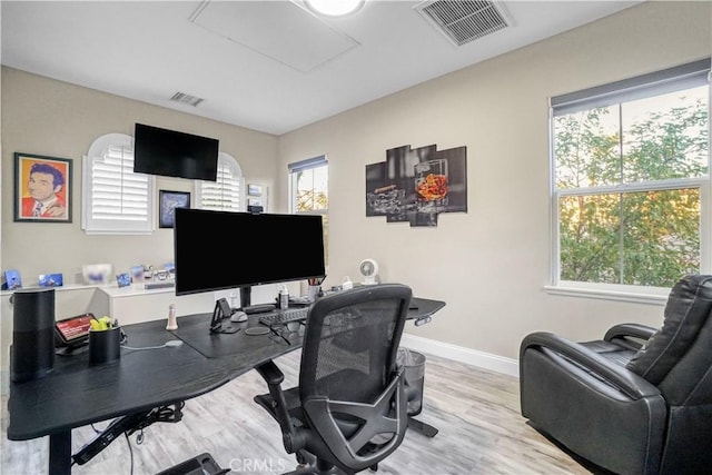 office space featuring baseboards, visible vents, and wood finished floors