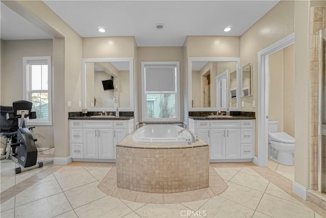 bathroom featuring tile patterned floors, tiled bath, vanity, and toilet