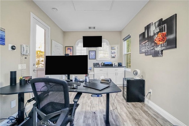 home office featuring baseboards, visible vents, a wealth of natural light, and light wood-style flooring