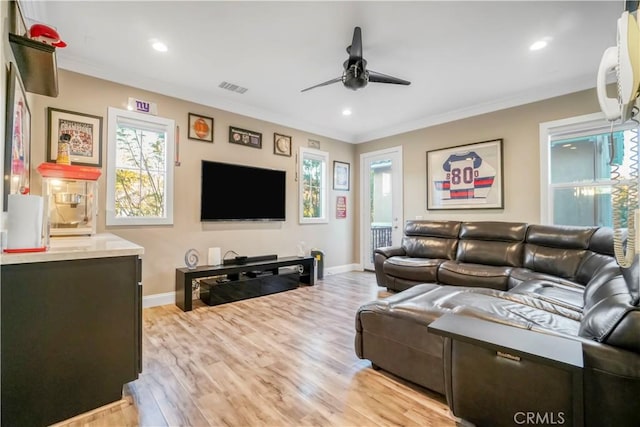 living room featuring ceiling fan, light hardwood / wood-style floors, a healthy amount of sunlight, and ornamental molding