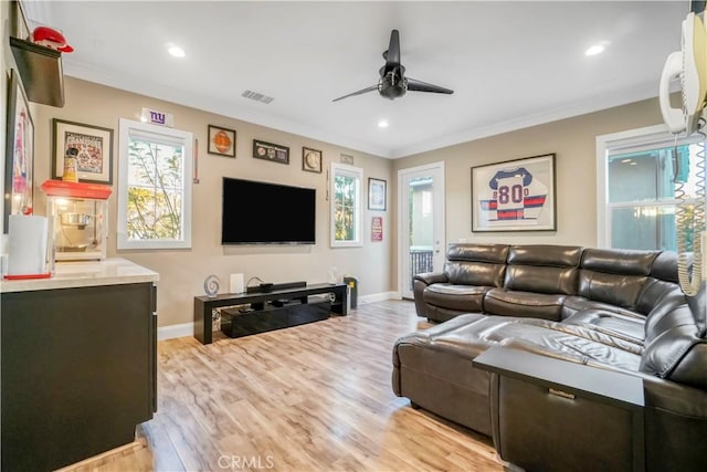 living room featuring visible vents, a healthy amount of sunlight, a ceiling fan, and ornamental molding
