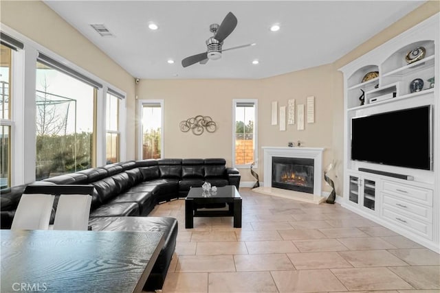 living room with built in shelves, ceiling fan, and light tile patterned floors