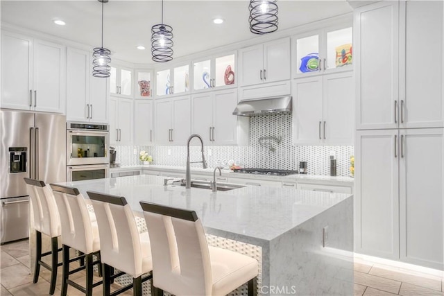 kitchen with a kitchen island with sink, sink, extractor fan, and appliances with stainless steel finishes