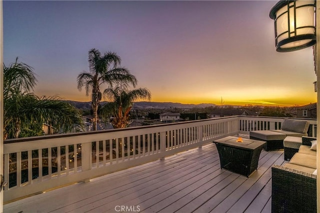 deck at dusk with an outdoor living space with a fire pit