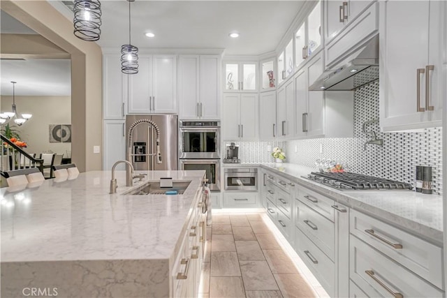 kitchen with white cabinetry, light stone countertops, tasteful backsplash, pendant lighting, and appliances with stainless steel finishes