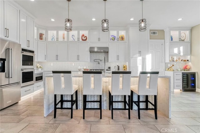 kitchen featuring beverage cooler, visible vents, stainless steel appliances, light countertops, and backsplash
