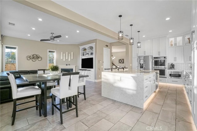 kitchen featuring appliances with stainless steel finishes, open floor plan, light stone counters, and recessed lighting