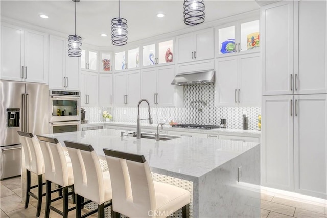 kitchen featuring a kitchen island with sink, stainless steel appliances, white cabinets, a sink, and ventilation hood