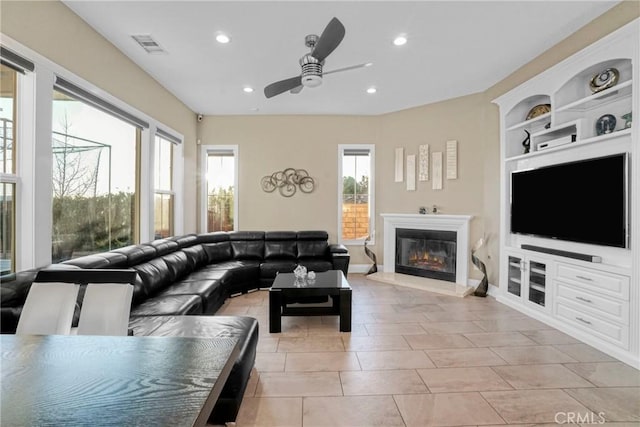living room with built in shelves, recessed lighting, ceiling fan, and a glass covered fireplace