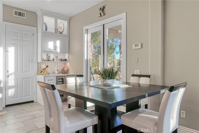 dining space featuring wine cooler, visible vents, and a bar