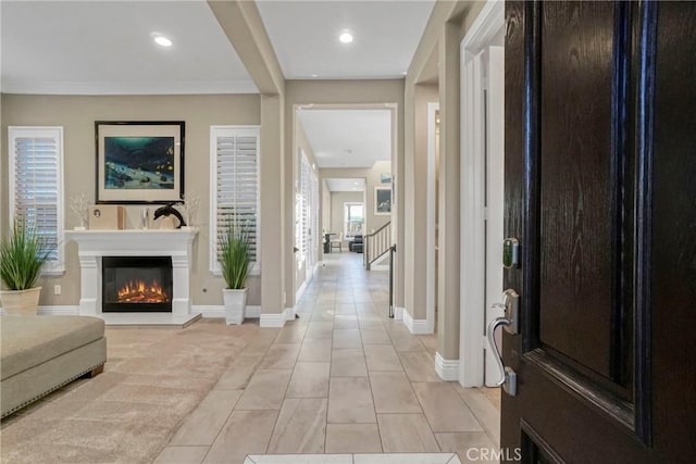 entrance foyer featuring recessed lighting, stairs, light tile patterned floors, a glass covered fireplace, and baseboards