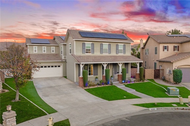 view of front of house featuring a garage, a porch, a yard, and solar panels