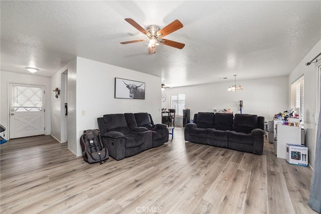 living room featuring a textured ceiling, ceiling fan with notable chandelier, and light wood-type flooring