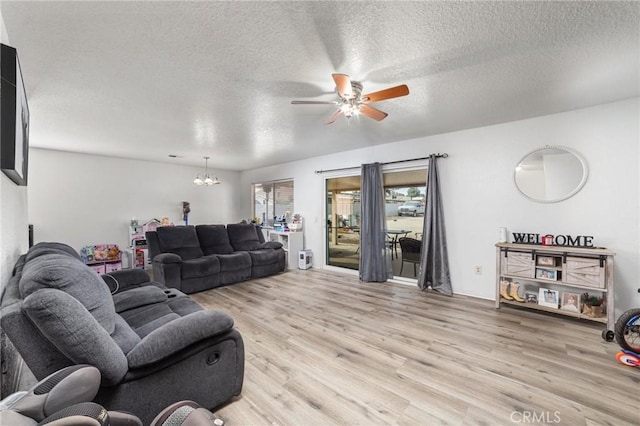 living room with ceiling fan with notable chandelier, a textured ceiling, and light wood-type flooring