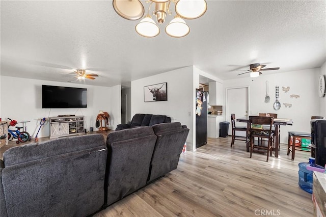 living room with a textured ceiling, light hardwood / wood-style floors, and an inviting chandelier