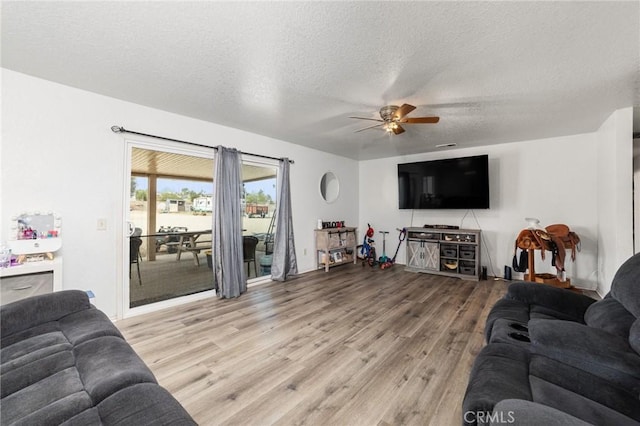 living room with a textured ceiling, light hardwood / wood-style floors, and ceiling fan