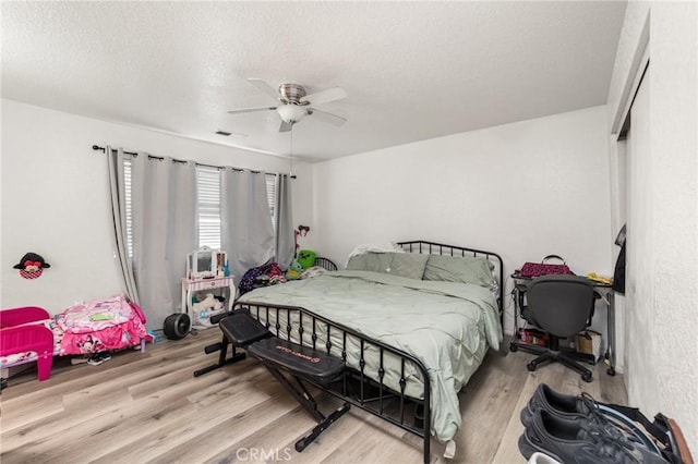 bedroom with ceiling fan, light hardwood / wood-style floors, a textured ceiling, and a closet