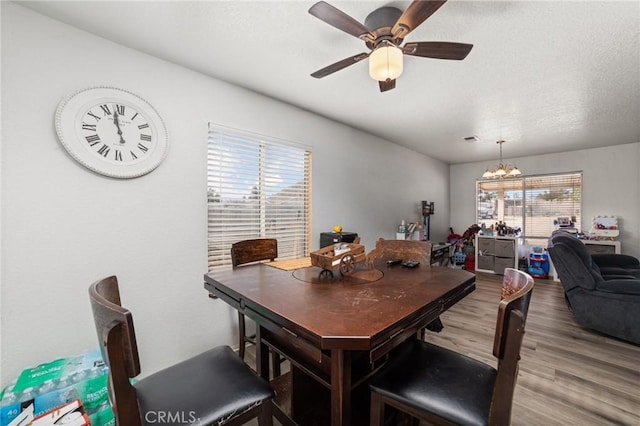 dining space featuring ceiling fan with notable chandelier and hardwood / wood-style flooring