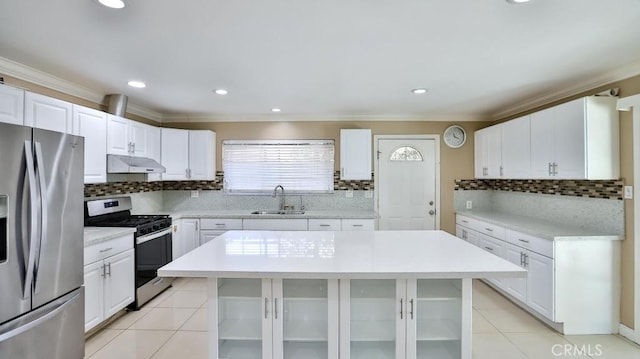 kitchen featuring decorative backsplash, stainless steel appliances, sink, a center island, and white cabinetry