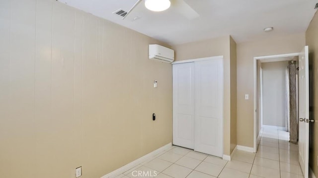 unfurnished bedroom with ceiling fan, an AC wall unit, light tile patterned floors, and a closet